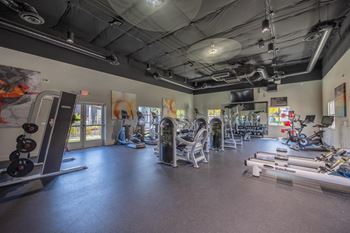 A gym with a variety of equipment including treadmills, weights, and exercise machines.